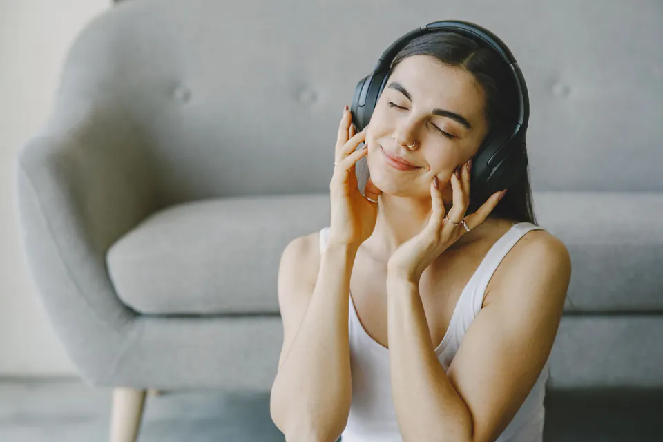 Une femme écoute de la musique au casque, les yeux fermés, en souriant