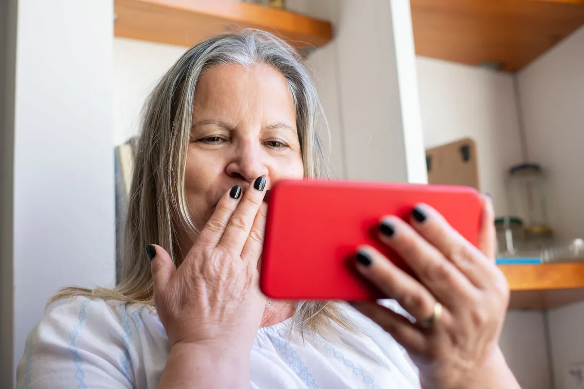 Une femme découvre quelque chose sur son téléphone, la main sur la bouche, émue
